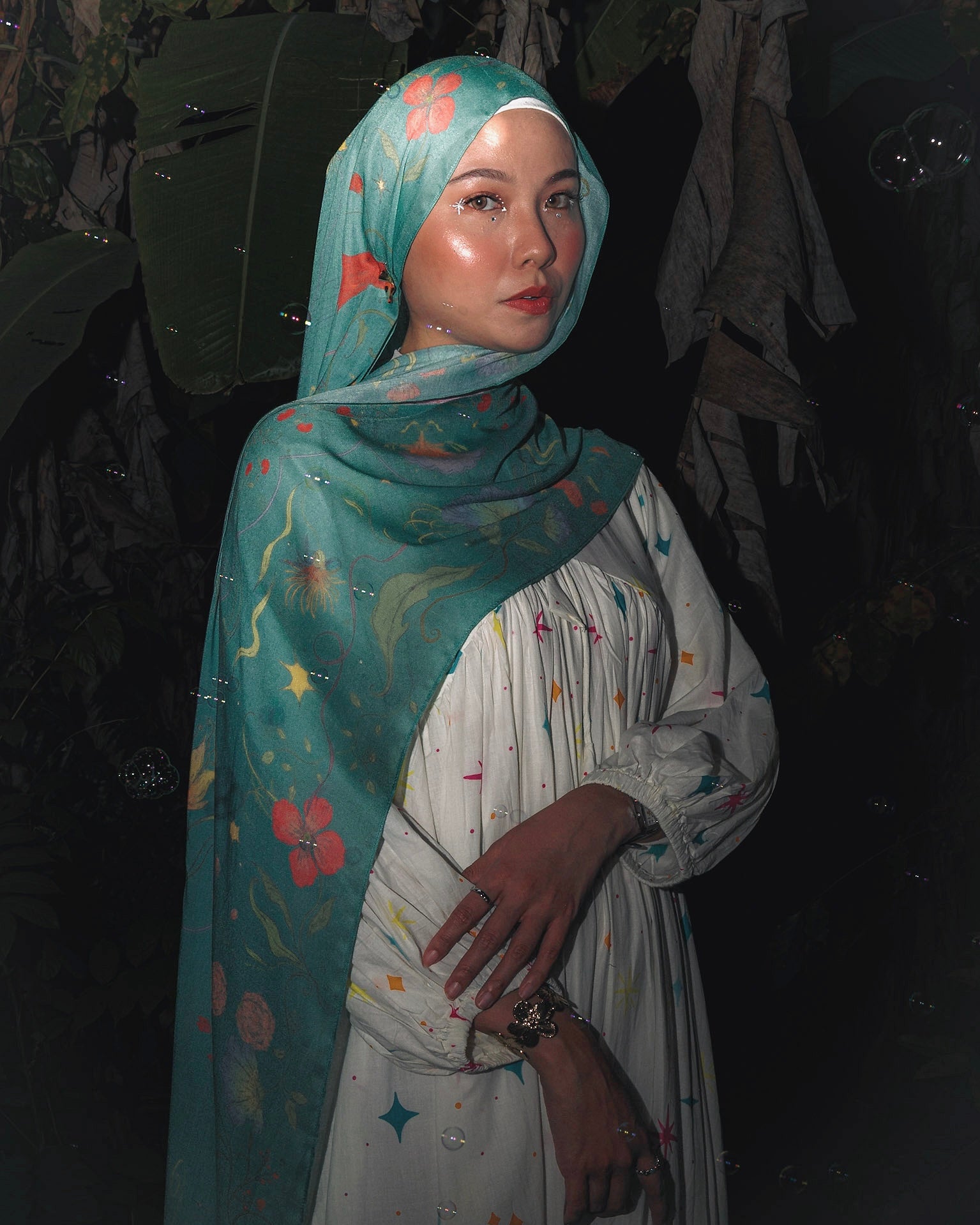 Model wearing Soof Fotosynthesia printed modal hijab scarf in teal.