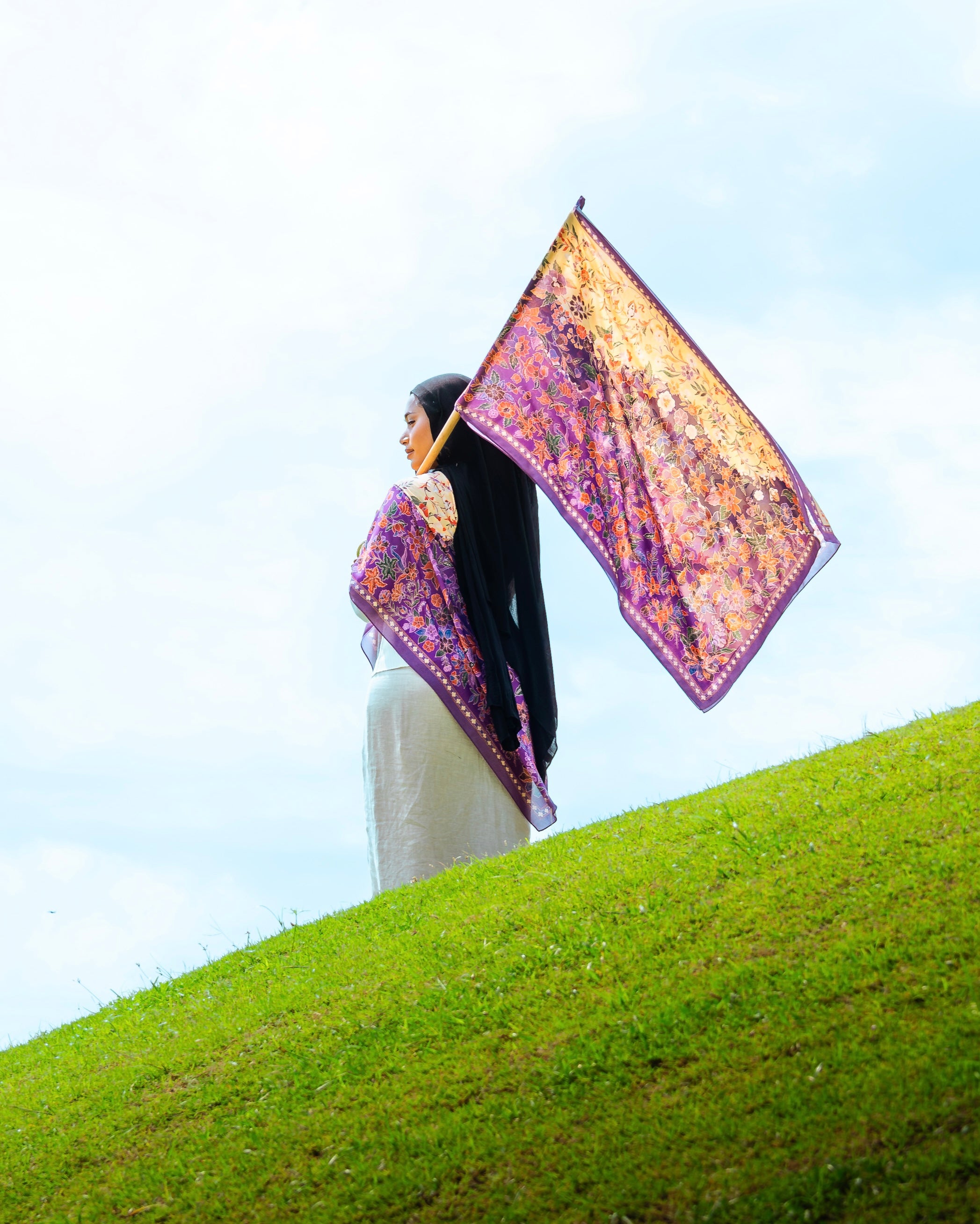 Woman wearing a Soof Sarung in Embun floral chiffon, purple and yellow headscarf.