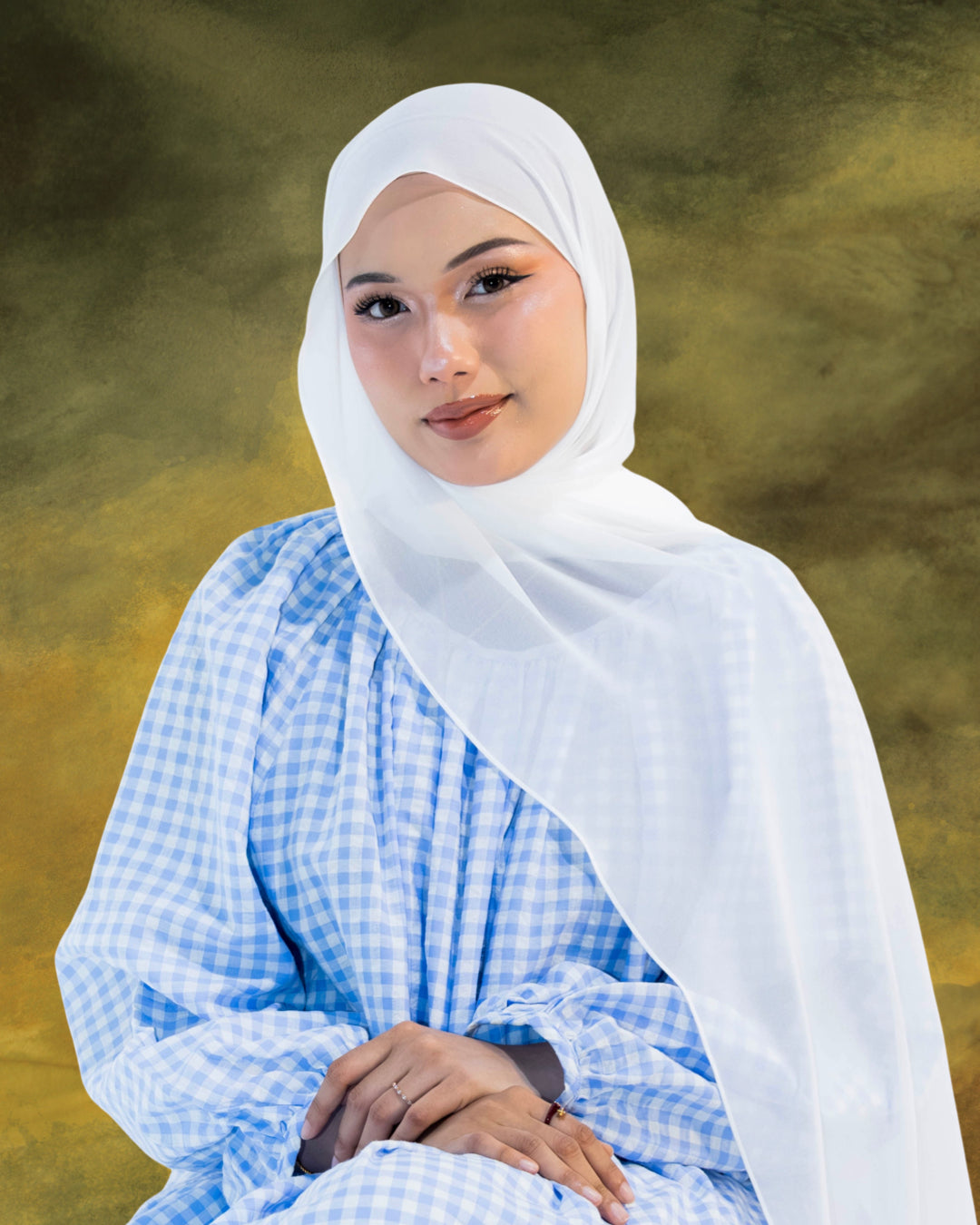 Woman wearing Soof Seracell hijab in Snow Veil and blue checkered dress against a green background