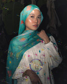 Model wearing Soof Fotosynthesia printed modal hijab scarf in teal.