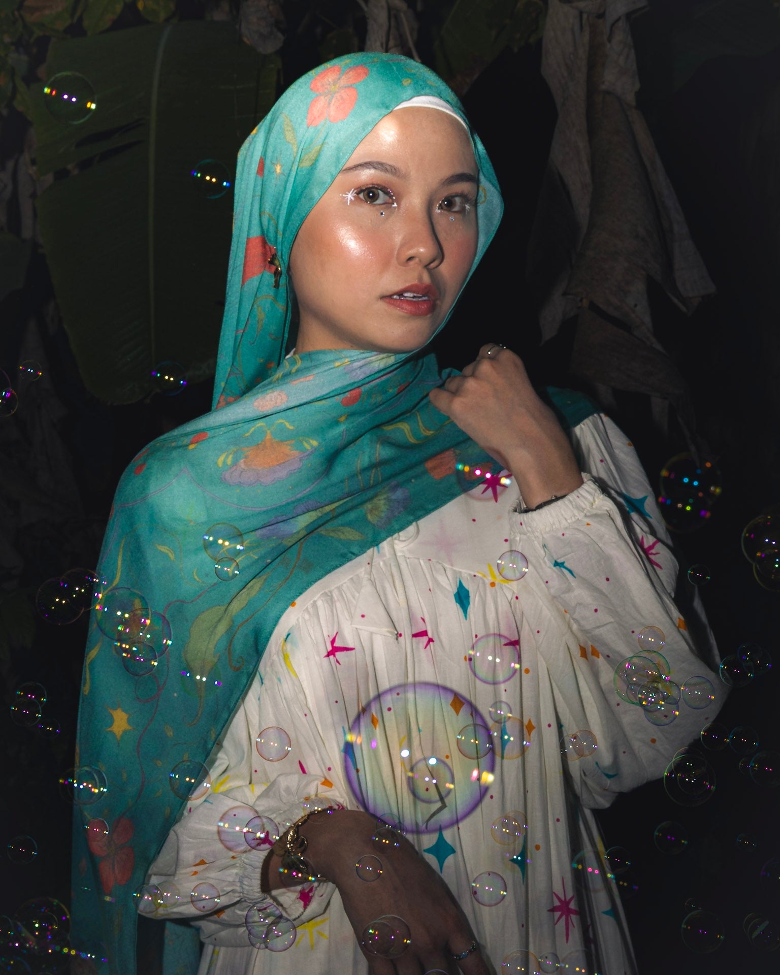 Model wearing Soof Fotosynthesia printed modal hijab scarf in teal.
