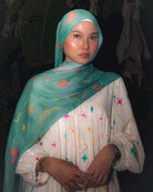 Model wearing Soof Fotosynthesia printed modal hijab scarf in teal.