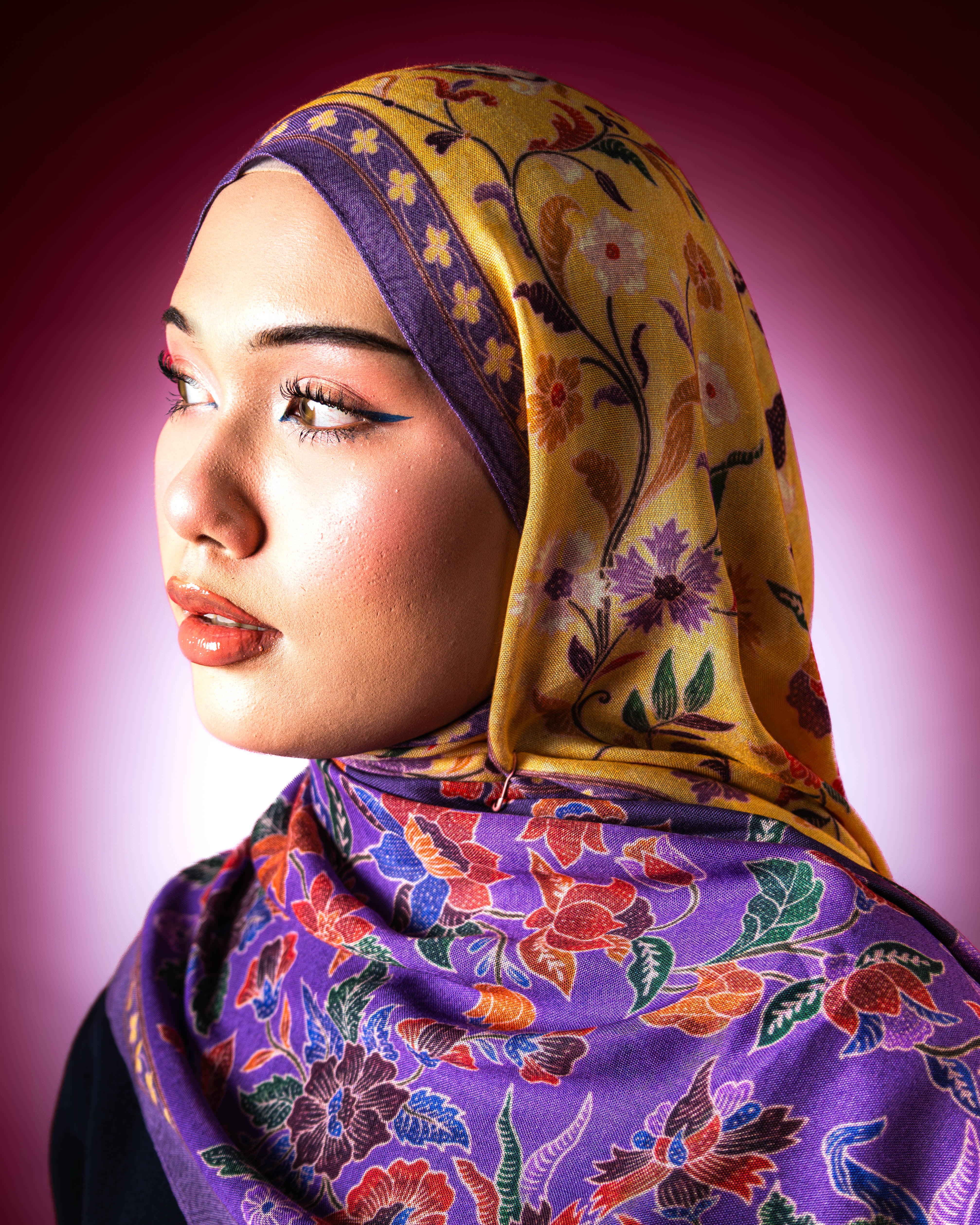 Woman wearing a Soof Sarung in Embun floral modal shawl, purple and yellow headscarf. 