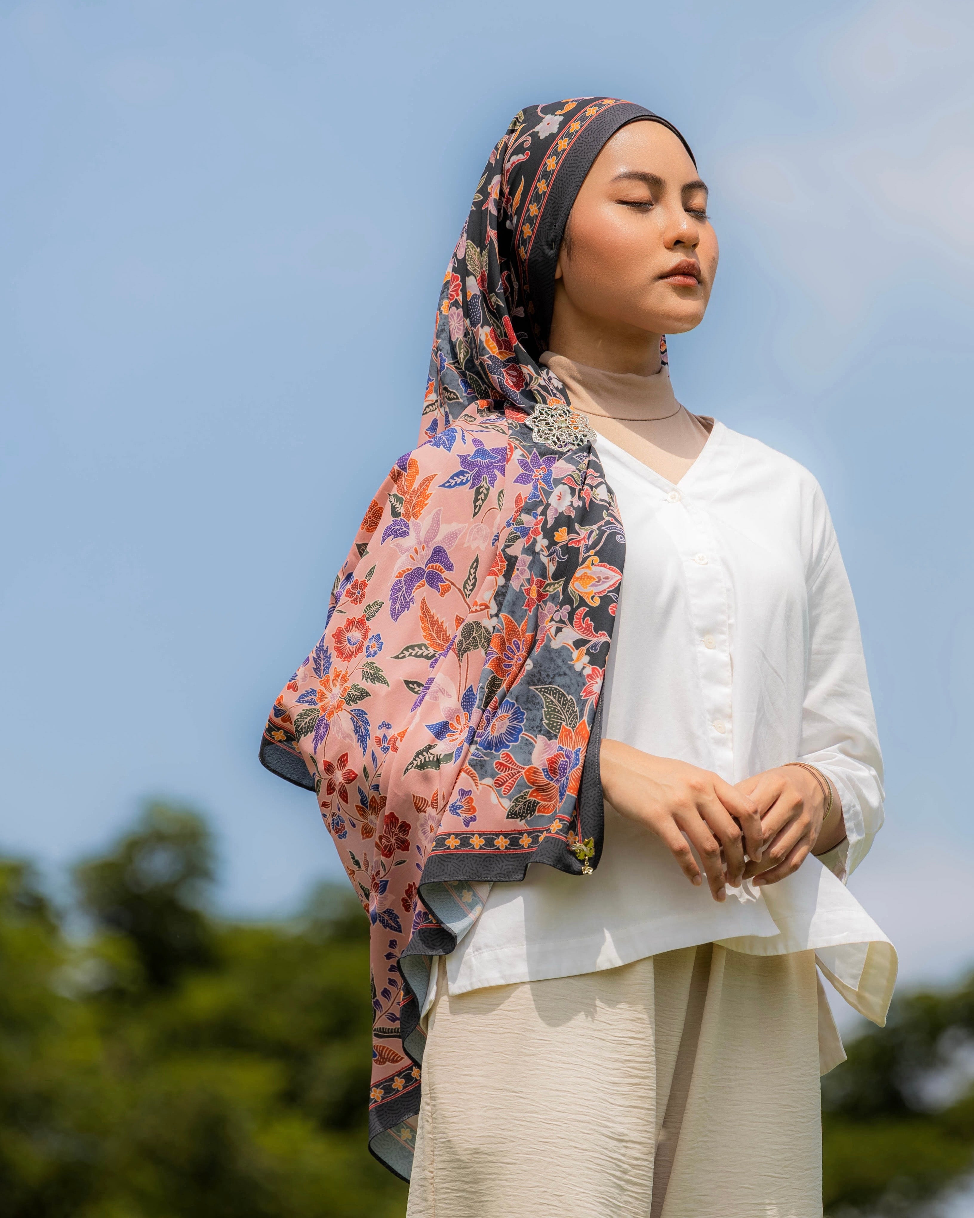 Woman wearing a Soof Sarung in Seri floral chiffon, black and pink headscarf. 