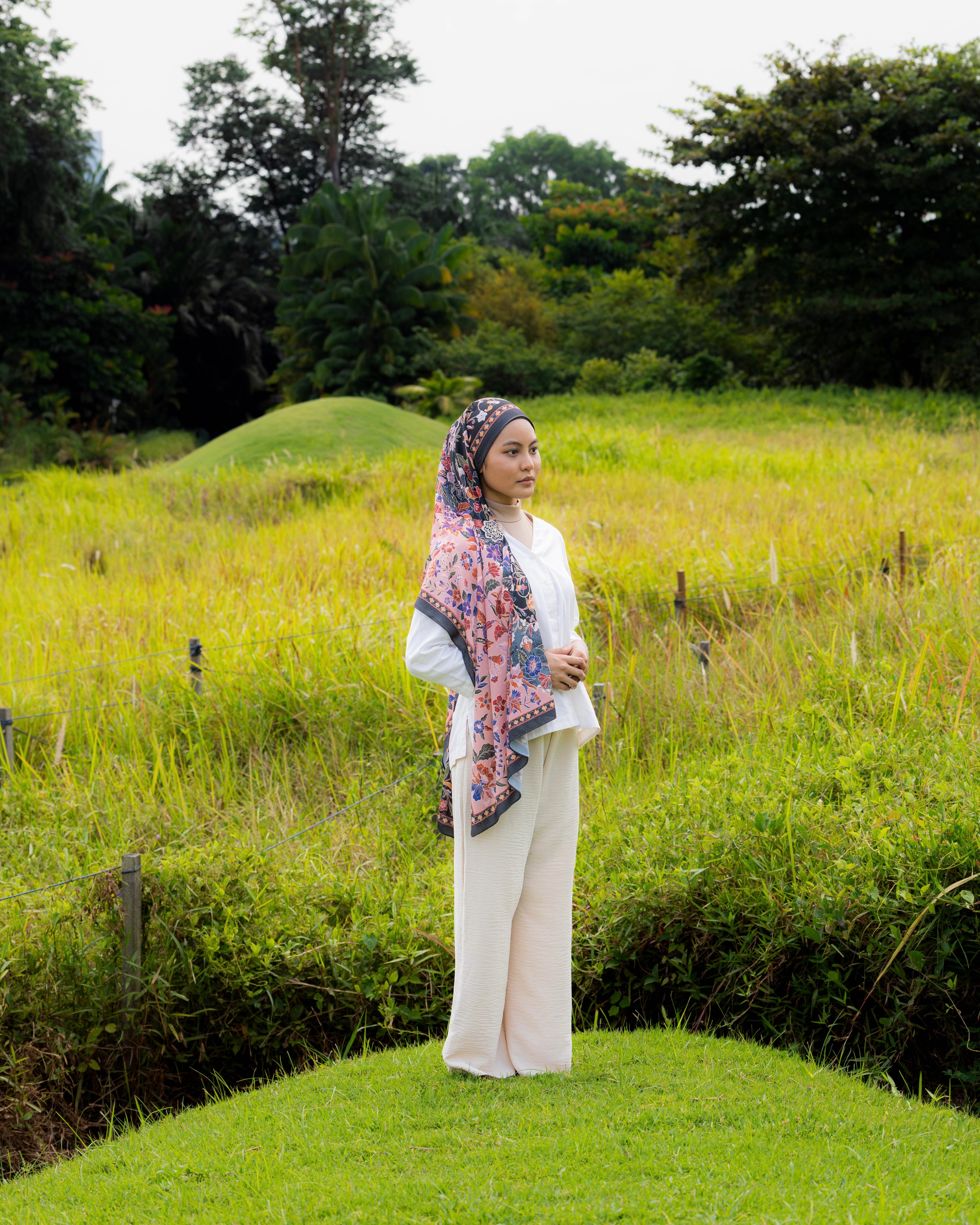 Woman wearing a Soof Sarung in Seri floral chiffon, black and pink headscarf. 
